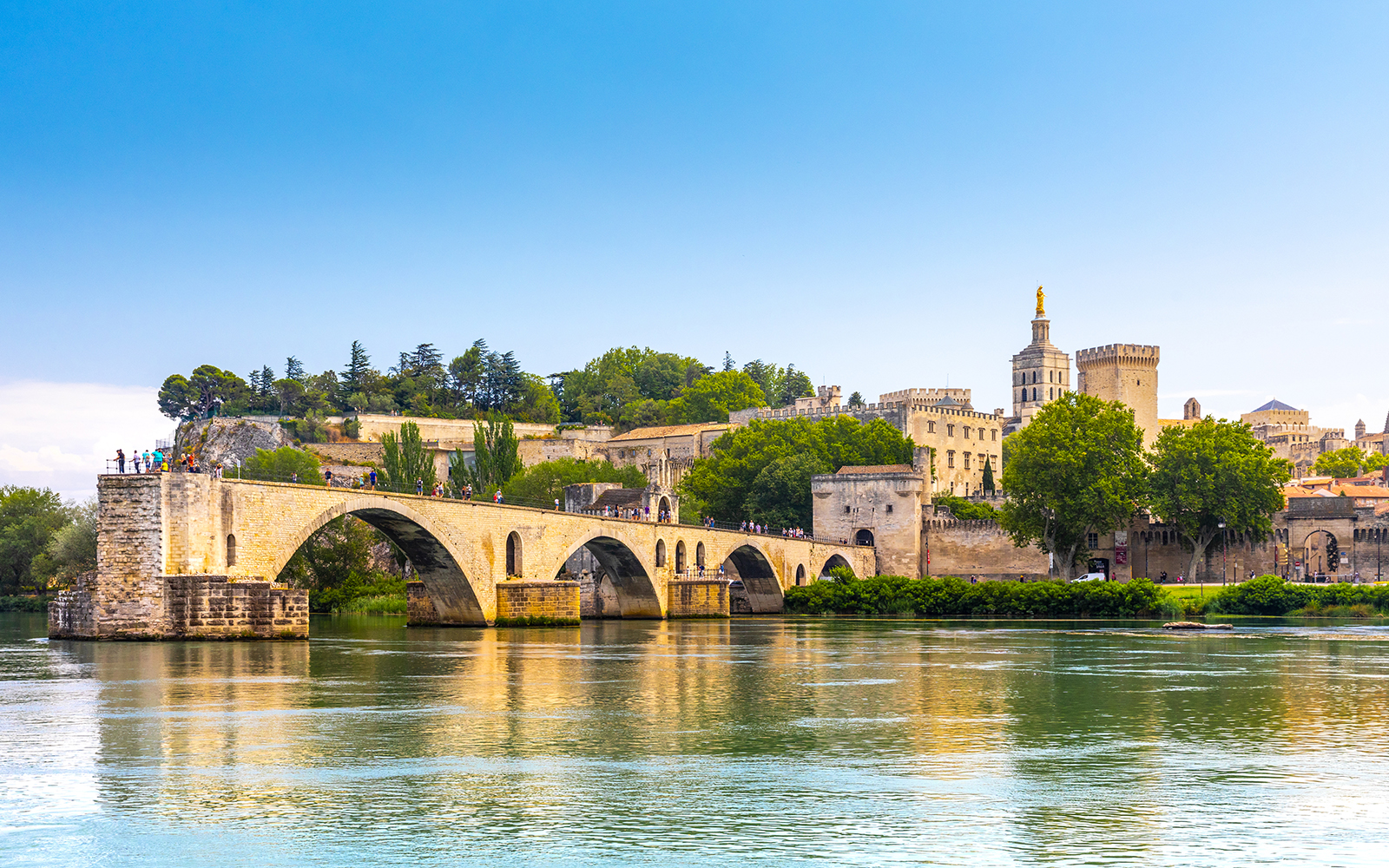 Palais de Papes and Avignon Cathedral at sunset with Pont Saint-Bénézet in foreground.