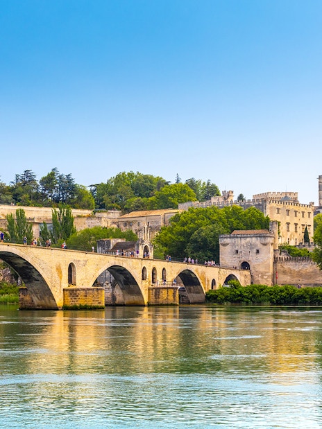 Palais de Papes and Avignon Cathedral at sunset with Pont Saint-Bénézet in foreground.