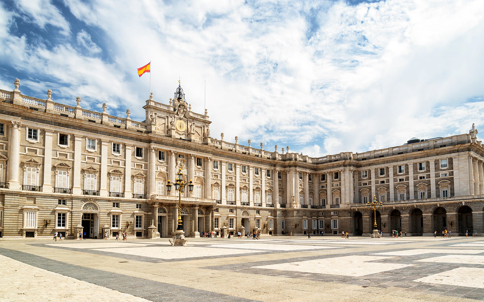 Royal Palace of Madrid exterior with Spanish flag and courtyard.