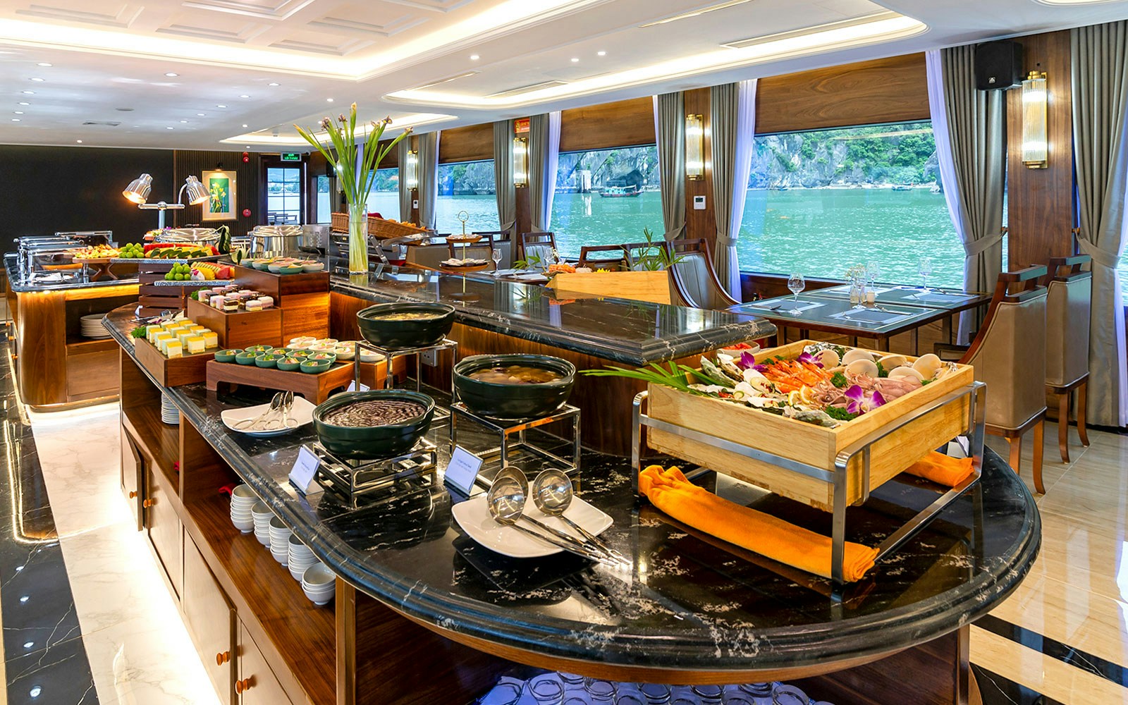 Luxurious dining area with buffet on Ha Long Bay 5-Star Cruise, featuring seafood and scenic views.