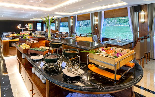 Luxurious dining area with buffet on Ha Long Bay 5-Star Cruise, featuring seafood and scenic views.