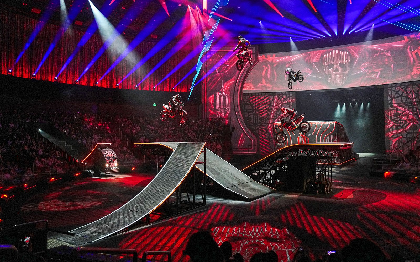 Motorcyclists performing stunts on ramps during House of Dancing Water show.