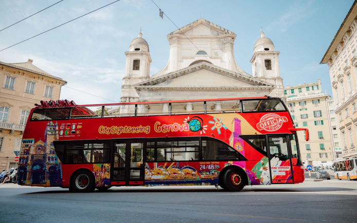 Red Genova sightseeing bus in front of historic church.