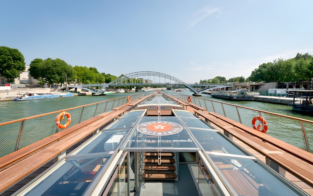 Seine River cruise boat approaching a bridge in Paris, France.