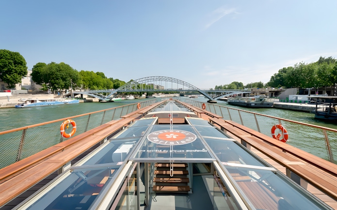 Seine River cruise boat approaching a bridge in Paris, France.