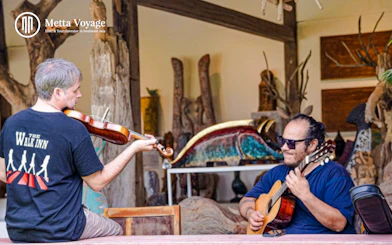 Musicians playing violin and guitar at Driftwood Village Hoi An wood carving workshop.