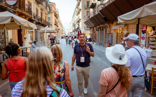 Tour guide leading a group through a historic street in Palermo, Italy.