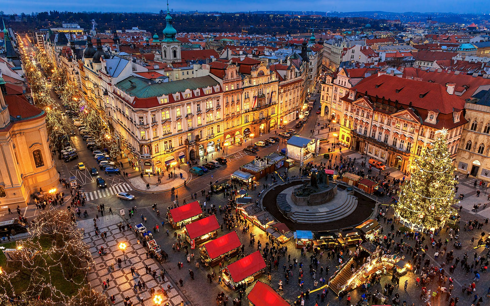 Old Town Square in Prague with Christmas market stalls and a lit Christmas tree.