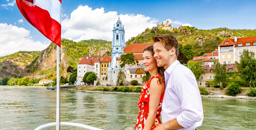 Couple enjoying a boat ride on the Danube River with Dürnstein Abbey in the background, Danube Valley tour from Vienna.