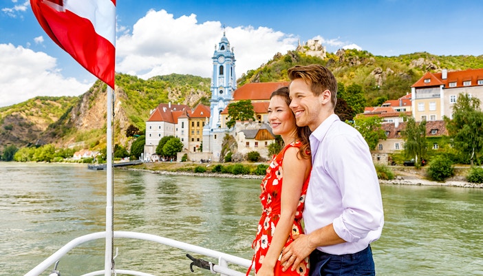 Couple enjoying a boat ride on the Danube River with Dürnstein Abbey in the background, Danube Valley tour from Vienna.