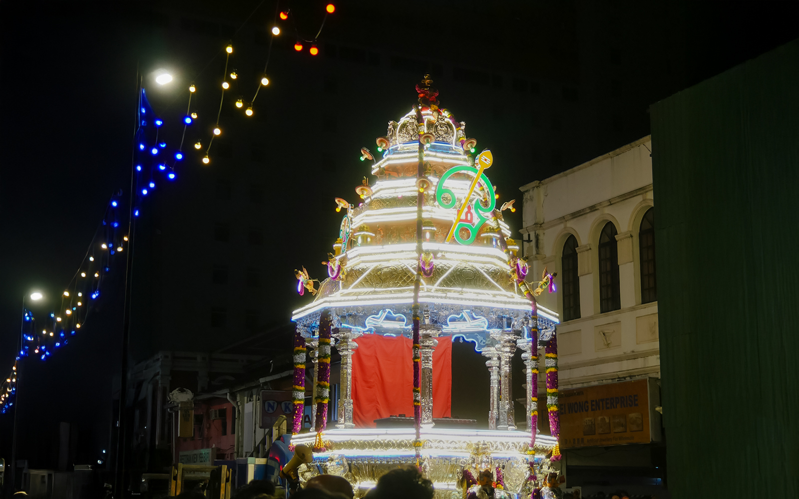 Silver chariot illuminated during Thaipusam festival procession at night.