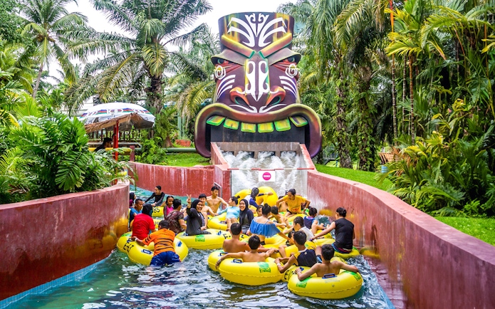 Visitors enjoying a water ride at A'Famosa Malacca, surrounded by lush greenery.
