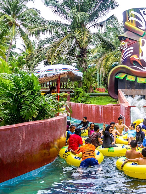 Visitors enjoying a water ride at A'Famosa Malacca, surrounded by lush greenery.