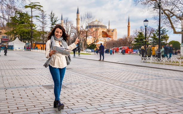 Tourist with map near Hagia Sophia, Istanbul, exploring traditional kebab and dervish ceremony experiences.