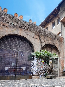 Juliet's balcony at Casa di Giulietta, Verona, with tourists in the courtyard.