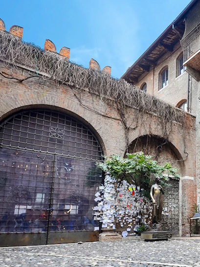 Juliet's balcony at Casa di Giulietta, Verona, with tourists in the courtyard.