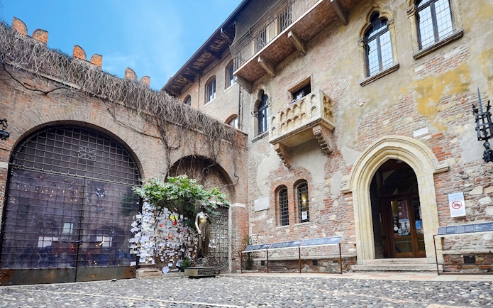 Juliet's balcony at Casa di Giulietta, Verona, with tourists in the courtyard.