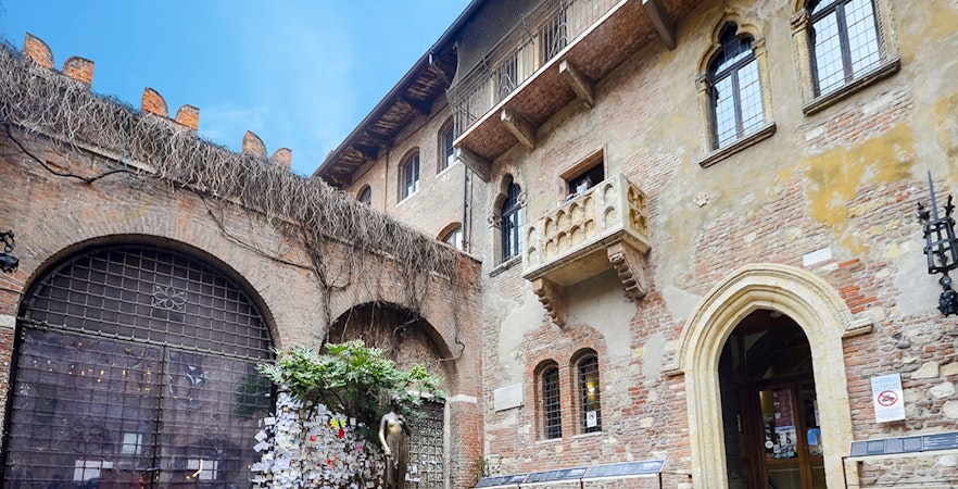 Juliet's balcony at Casa di Giulietta, Verona, with tourists in the courtyard.