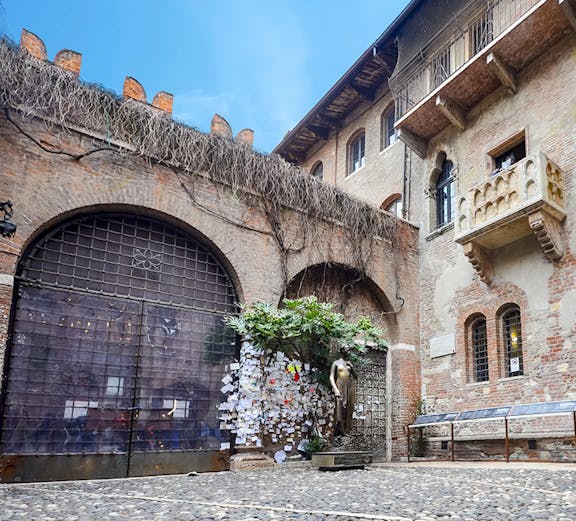 Juliet's balcony at Casa di Giulietta, Verona, with tourists in the courtyard.