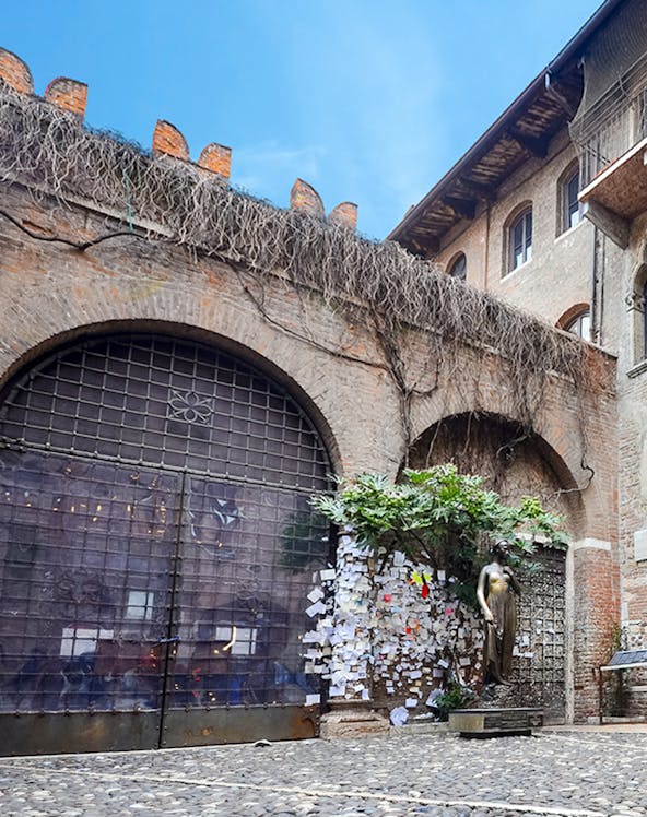 Juliet's balcony at Casa di Giulietta, Verona, with tourists in the courtyard.