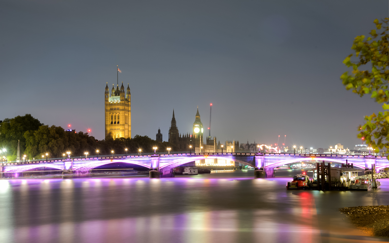 Westminster Bridge and Big Ben illuminated at night on the Thames River, London, UK.