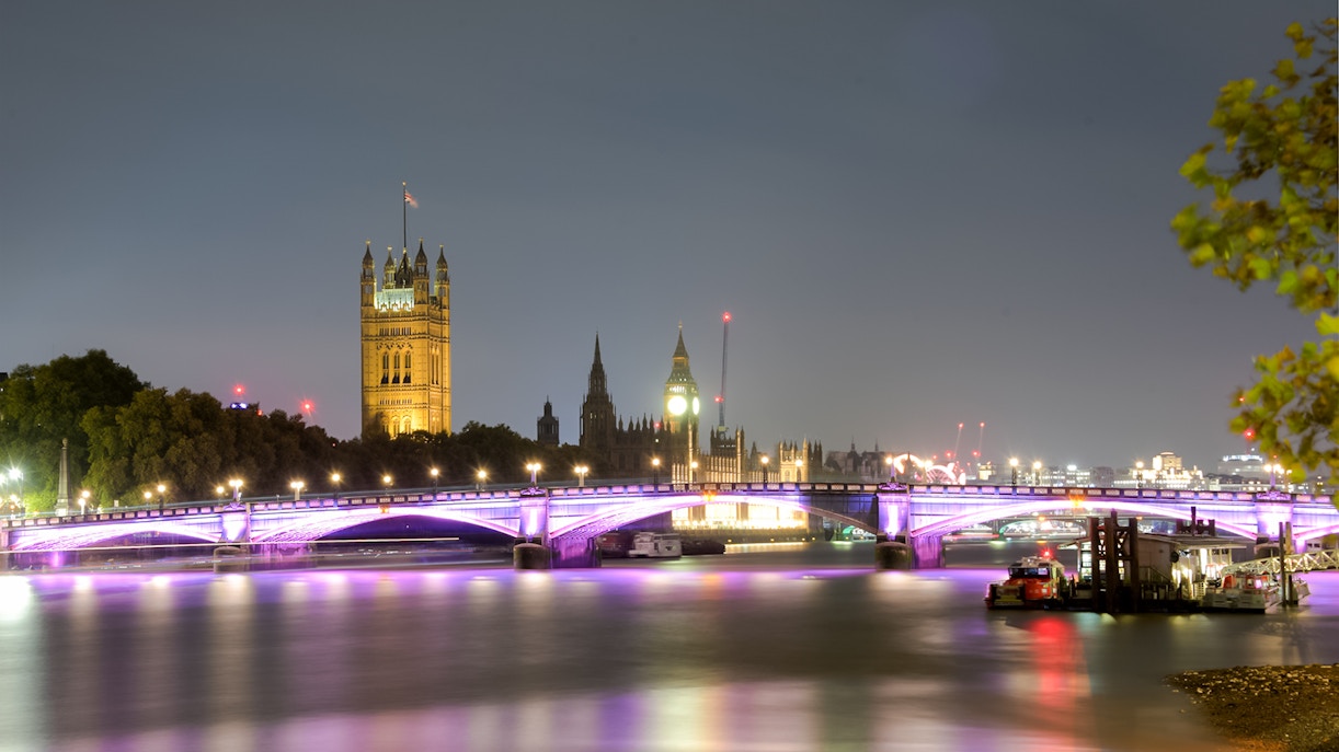 Westminster Bridge and Big Ben illuminated at night on the Thames River, London, UK.