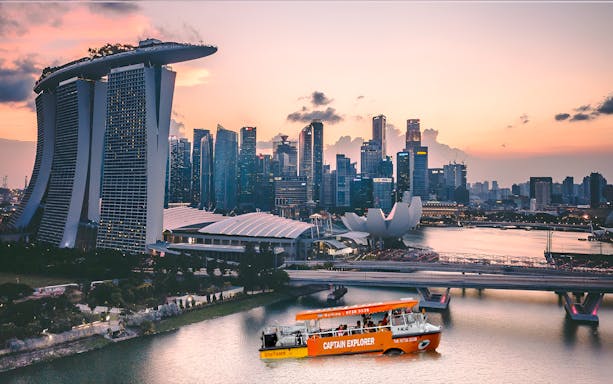 Singapore skyline at sunset with a cruise boat on Marina Bay.