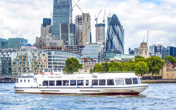 Sightseeing cruise boat on the Thames River with London skyline in the background.