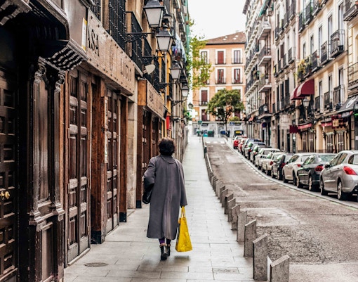 Street view in Barrio de La Latina, Madrid, with a person walking past traditional buildings.