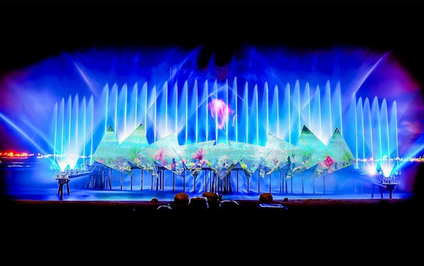 Colorful fountains and laser projections at Singapore's Wings of Time nighttime show.