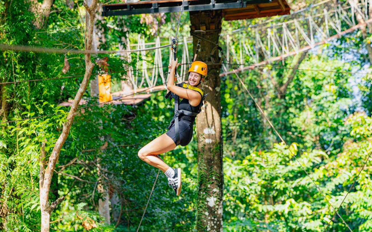 Ziplining through lush forest at SKY ROCK eco-adventure, Thailand.