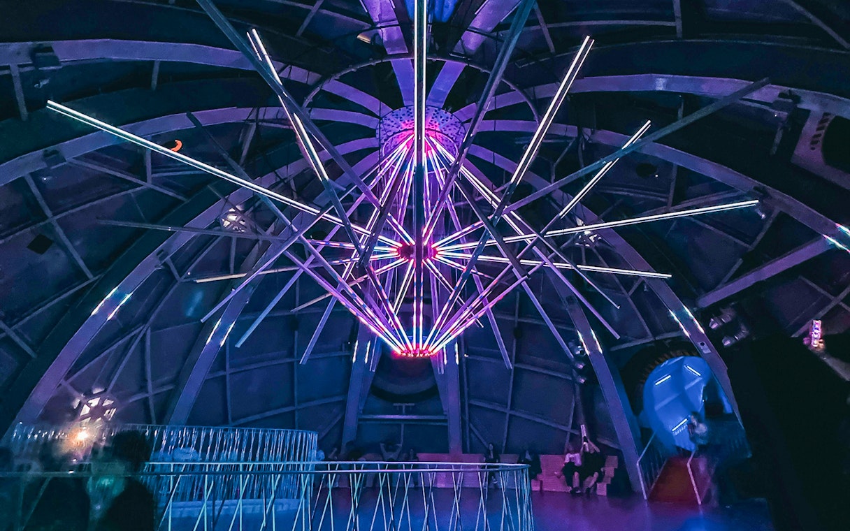 Illuminated interior structure of the Atomium in Brussels with colorful lights.