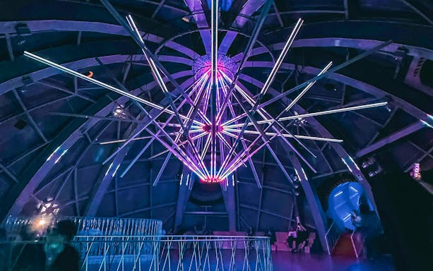Illuminated interior structure of the Atomium in Brussels with colorful lights.