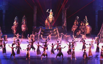 Phuket FantaSea Show performers in traditional costumes with elephants on stage.