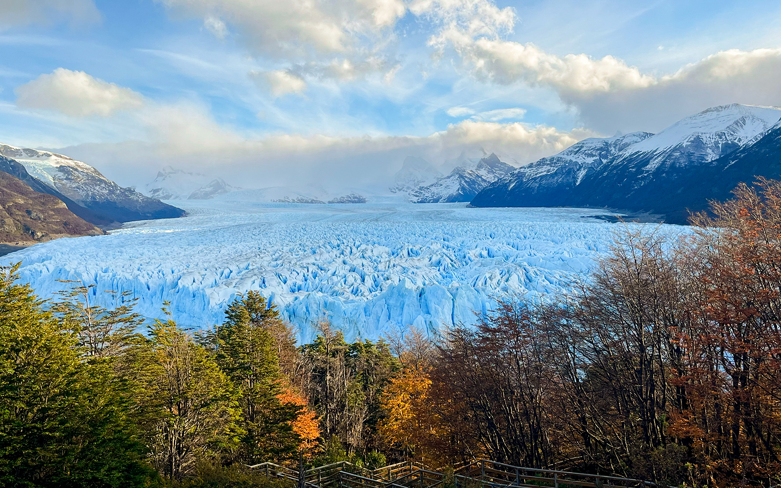 Perito Moreno Glacier in Argentina with surrounding mountains and autumn trees.