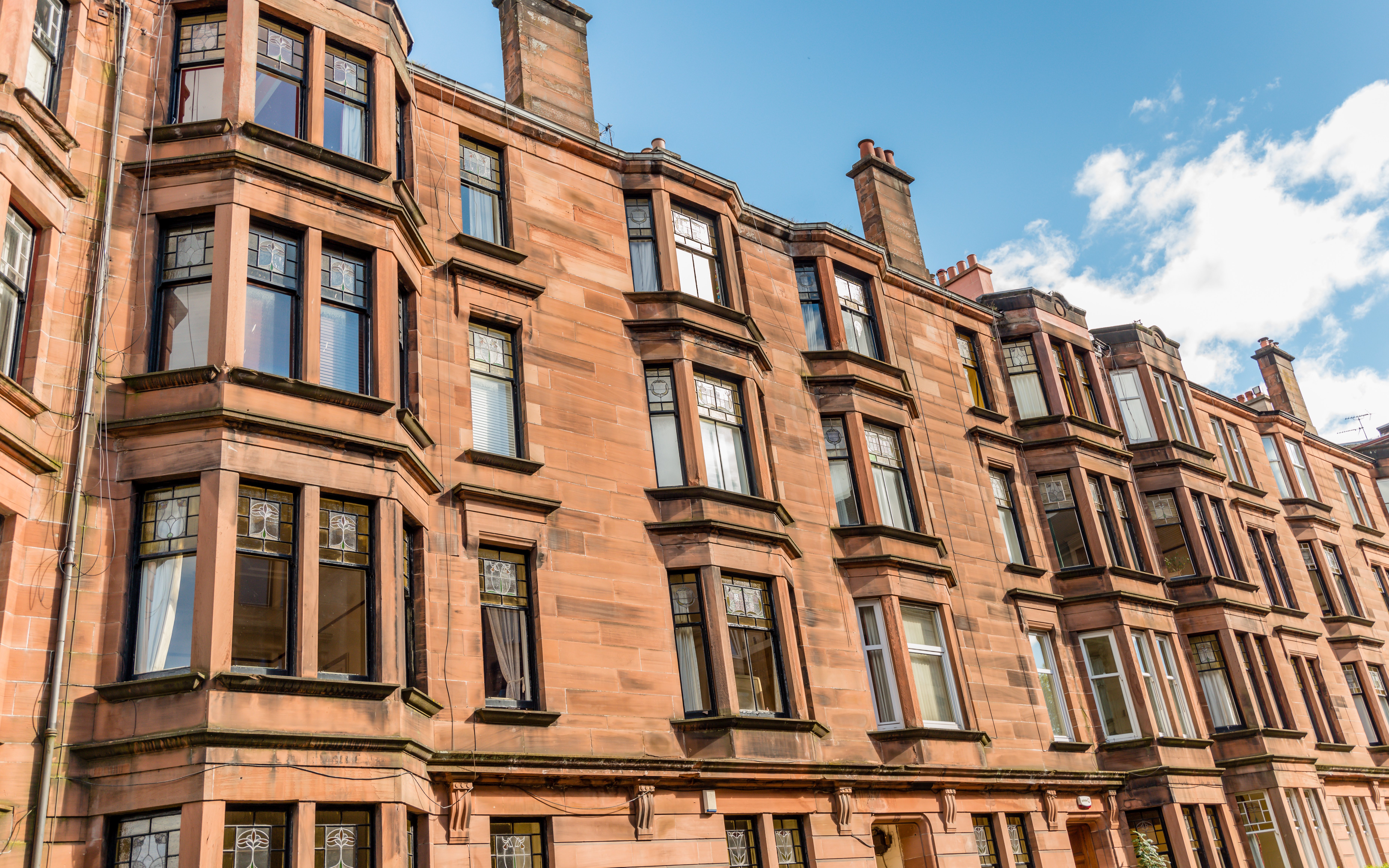 Tenement building facade in Glasgow with bay windows and sandstone exterior.