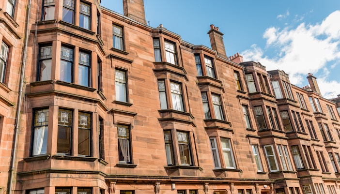 Tenement building facade in Glasgow with bay windows and sandstone exterior.