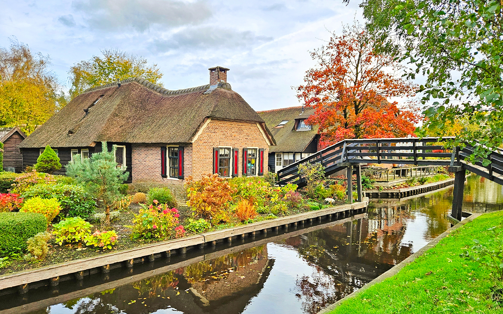 Thatched-roof house and wooden bridge over canal in Giethoorn, Netherlands.