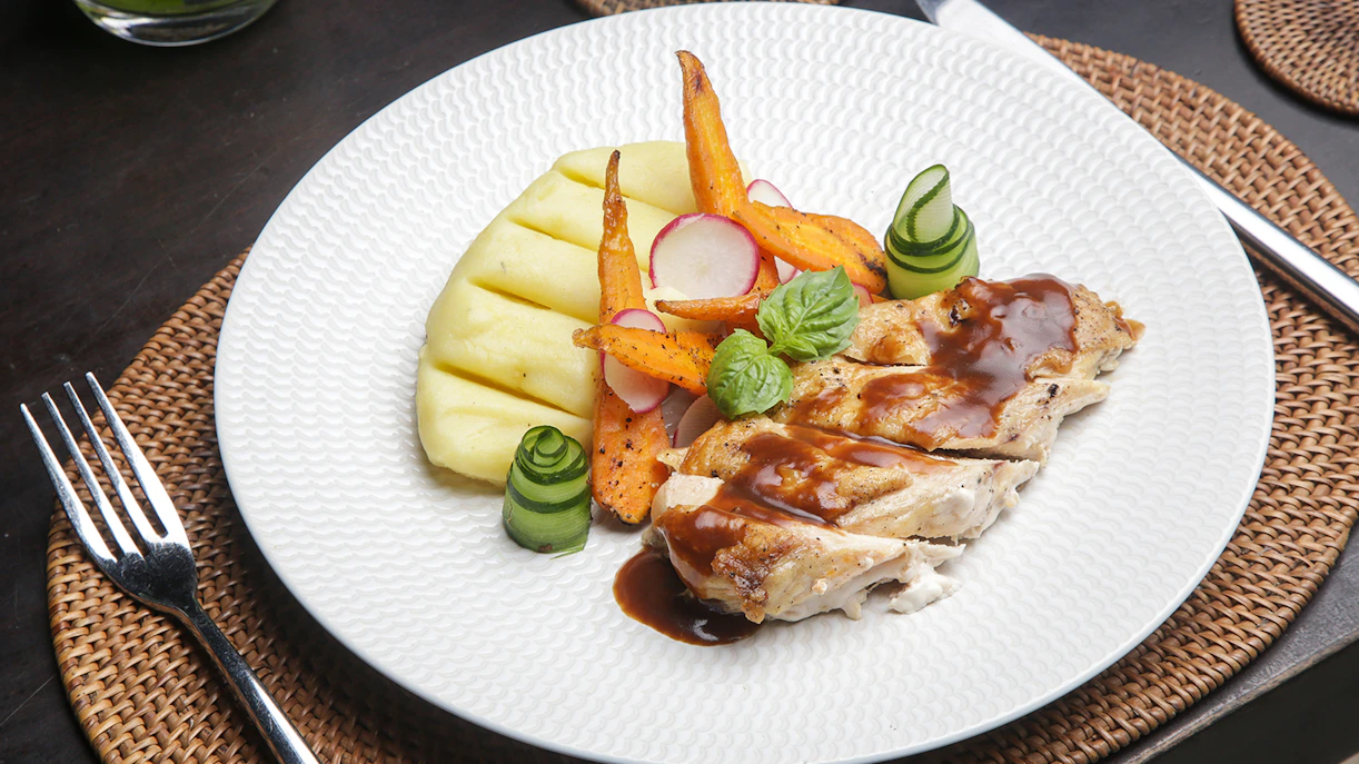 Grilled chicken with sauce, mashed potatoes, and vegetables on a Berlin cruise dinner plate.