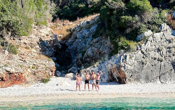 Tourists on a rocky beach at Sazan Island, Albania, near Haxhi Ali Cave.