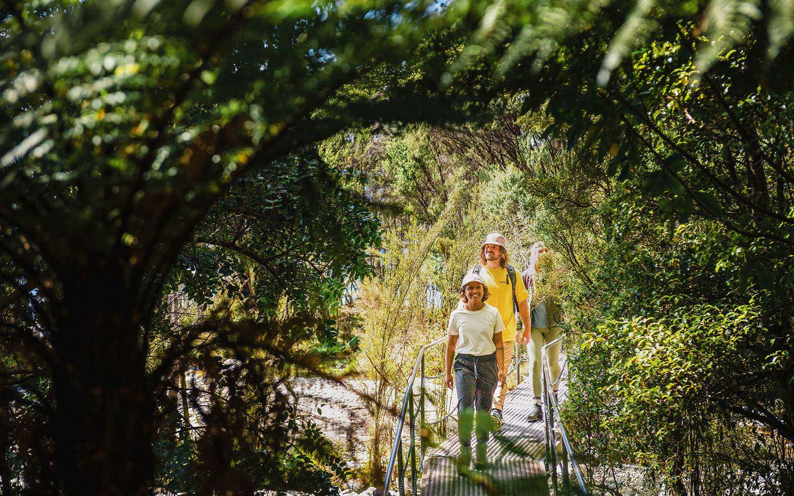 Tourists walking through lush forest on Te Anau Glowworm Caves guided tour.