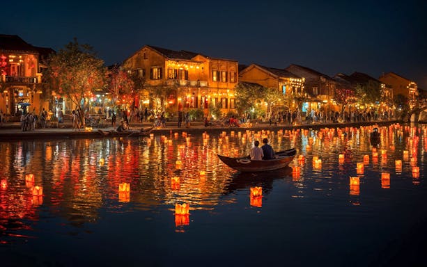 Lanterns floating on Hoi An river during evening release ceremony, Vietnam.