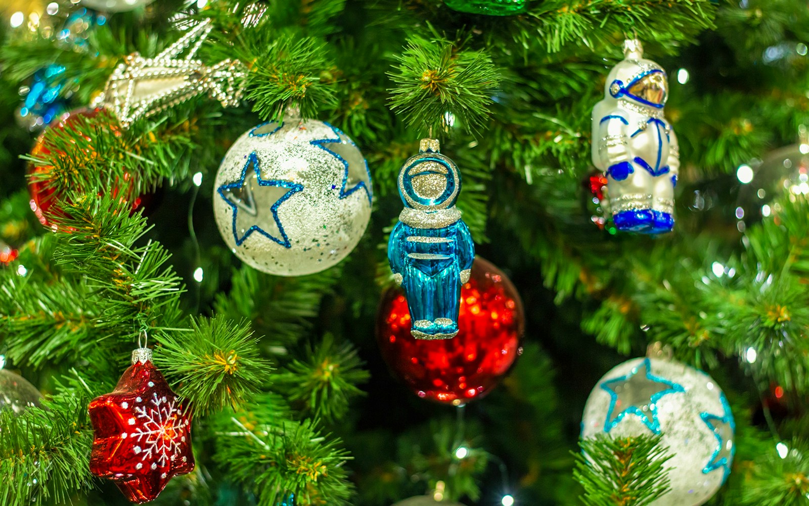 Christmas tree with colorful red balls, star ornaments, and astronaut decorations.
