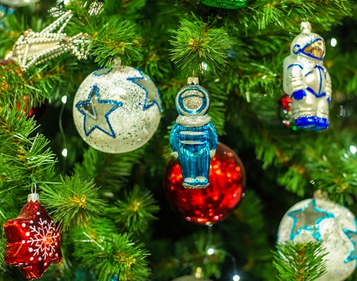 Christmas tree with colorful red balls, star ornaments, and astronaut decorations.