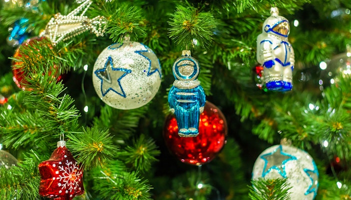 Christmas tree with colorful red balls, star ornaments, and astronaut decorations.