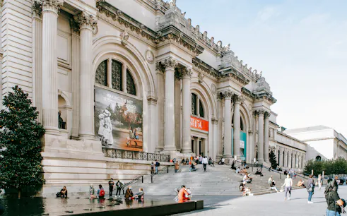 Exterior of The Metropolitan Museum of Art, New York City, with visitors on steps.