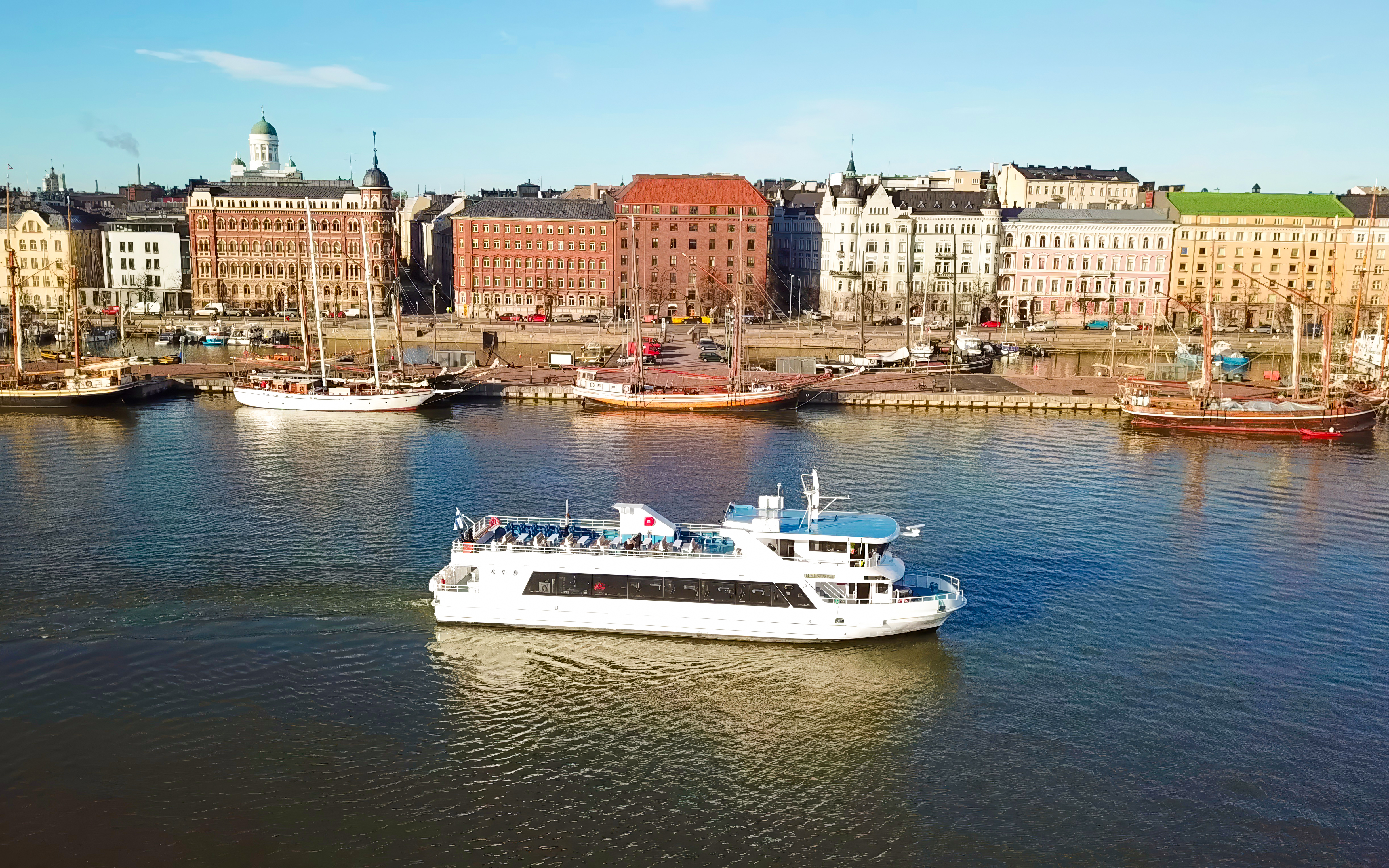 Helsinki sightseeing cruise ship on water with cityscape in background.