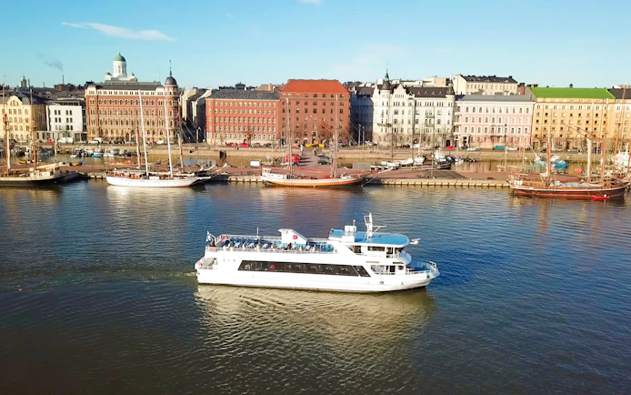 Helsinki sightseeing cruise ship on water with cityscape in background.