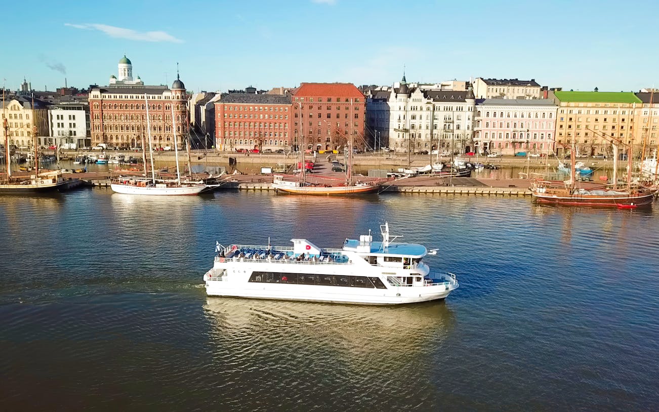 Helsinki sightseeing cruise ship on water with cityscape in background.