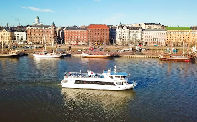 Helsinki sightseeing cruise ship on water with cityscape in background.
